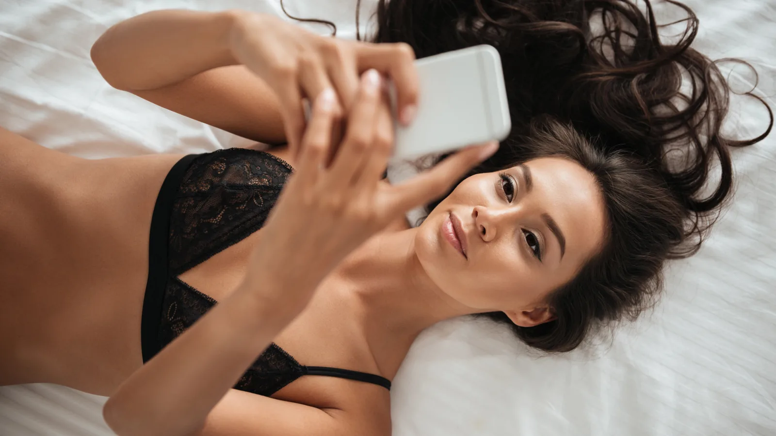 Hôtesse allongée, téléphone à la main, prête pour un appel de téléphone rose en Belgique